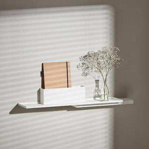 White Duplex Shelf by Puik hanging on a while with a plant and journal.
