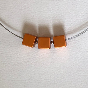 Three lightweight metal orange cubes on silver necklace by MOOI